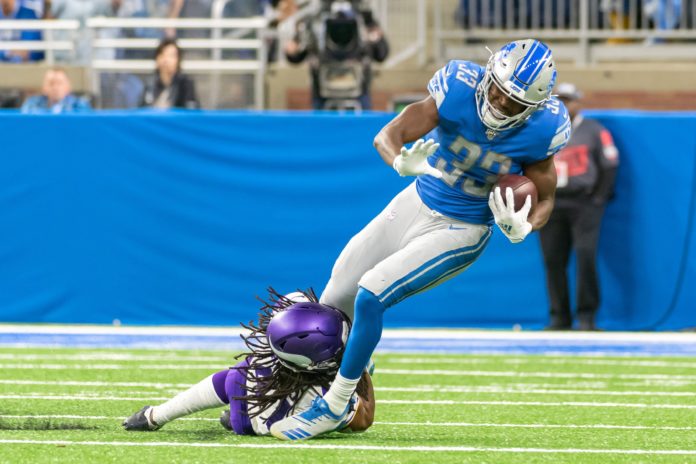 Detroit Lions RB Kerryon Johnson (33) gets tackled by Minnesota Vikings S Anthony Harris in a 2019 match.